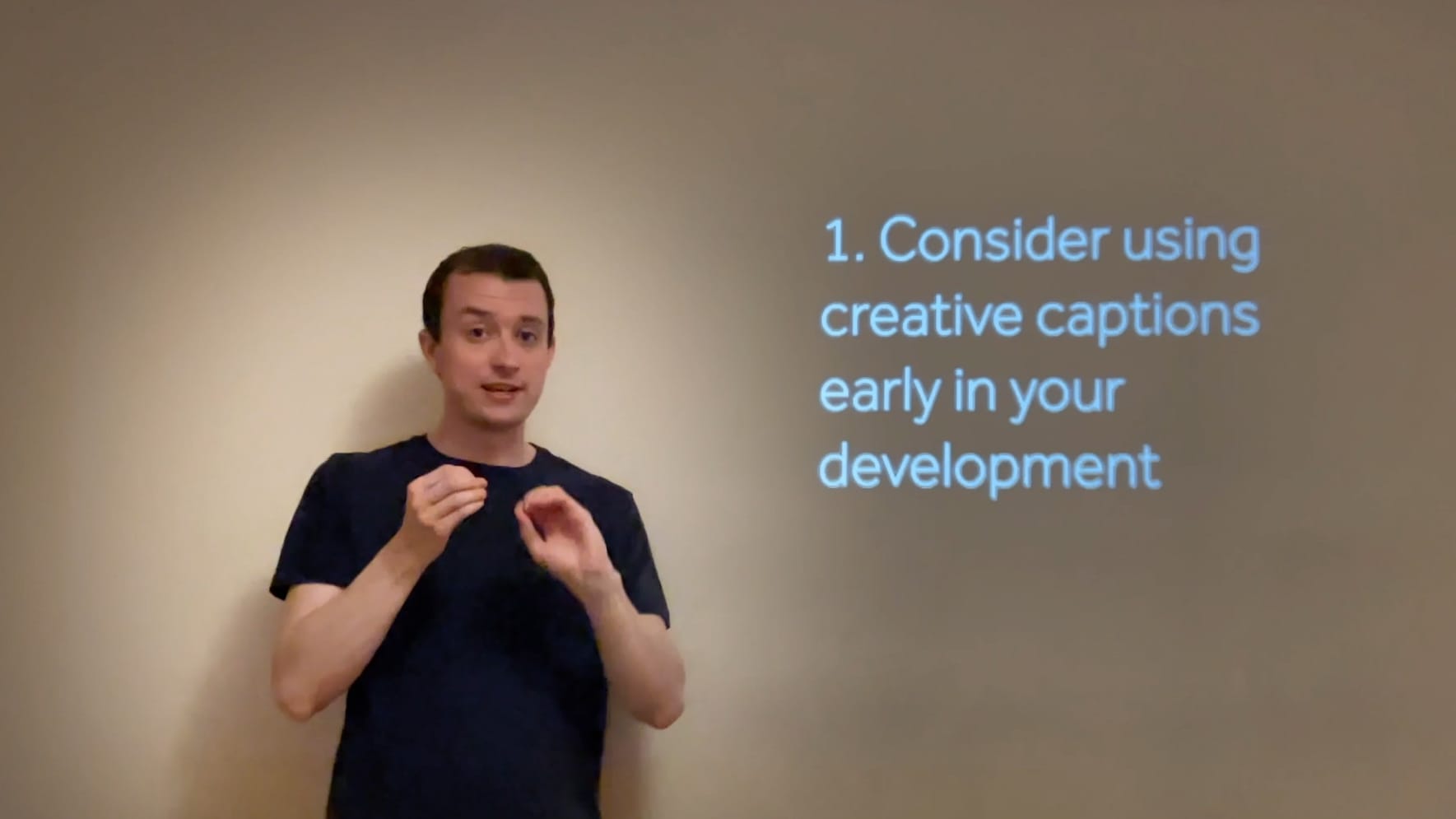 A man signing in front of captions saying 1. Consider using creative captions early in your development